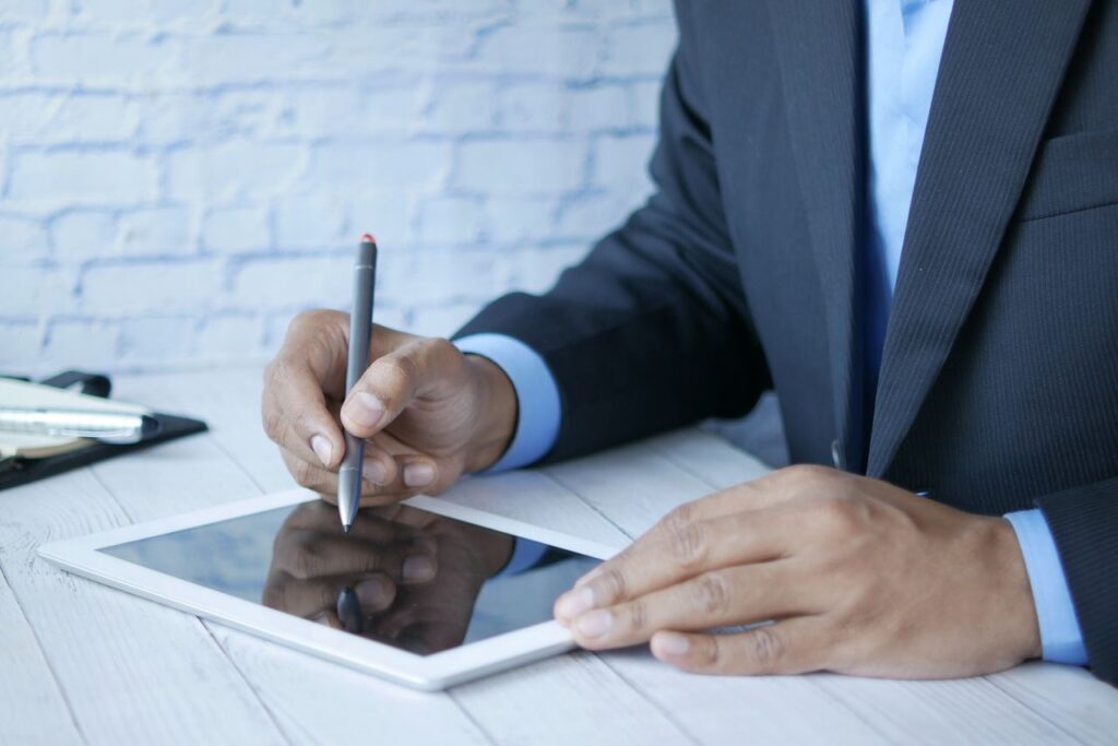 Seorang profesional menggunakan stylus untuk membubuhkan tanda tangan elektronik pada tablet demi akurasi pelacakan audit trail.